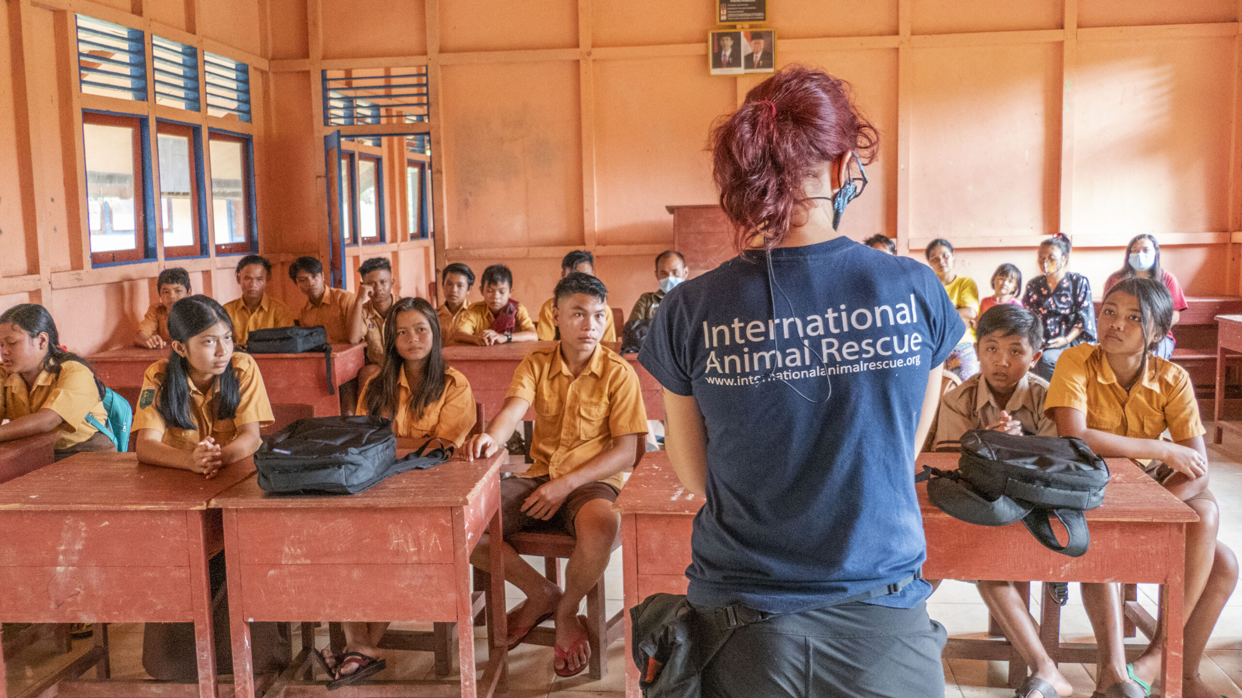 Children sitting in a classroom with a teacher wearing an International Animal Rescue T Shirt.
