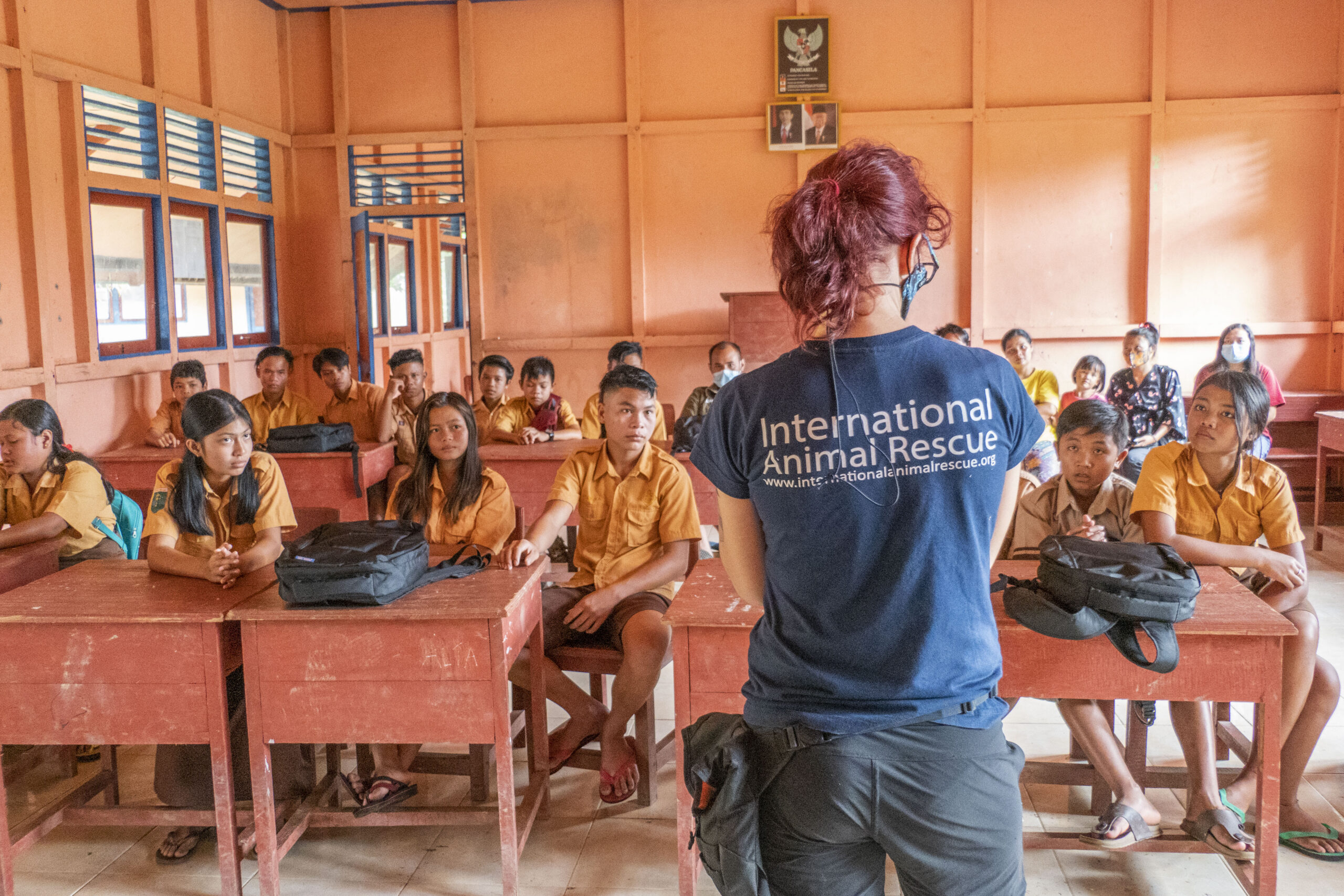 Children sitting in a classroom with a teacher wearing an International Animal Rescue T Shirt.
