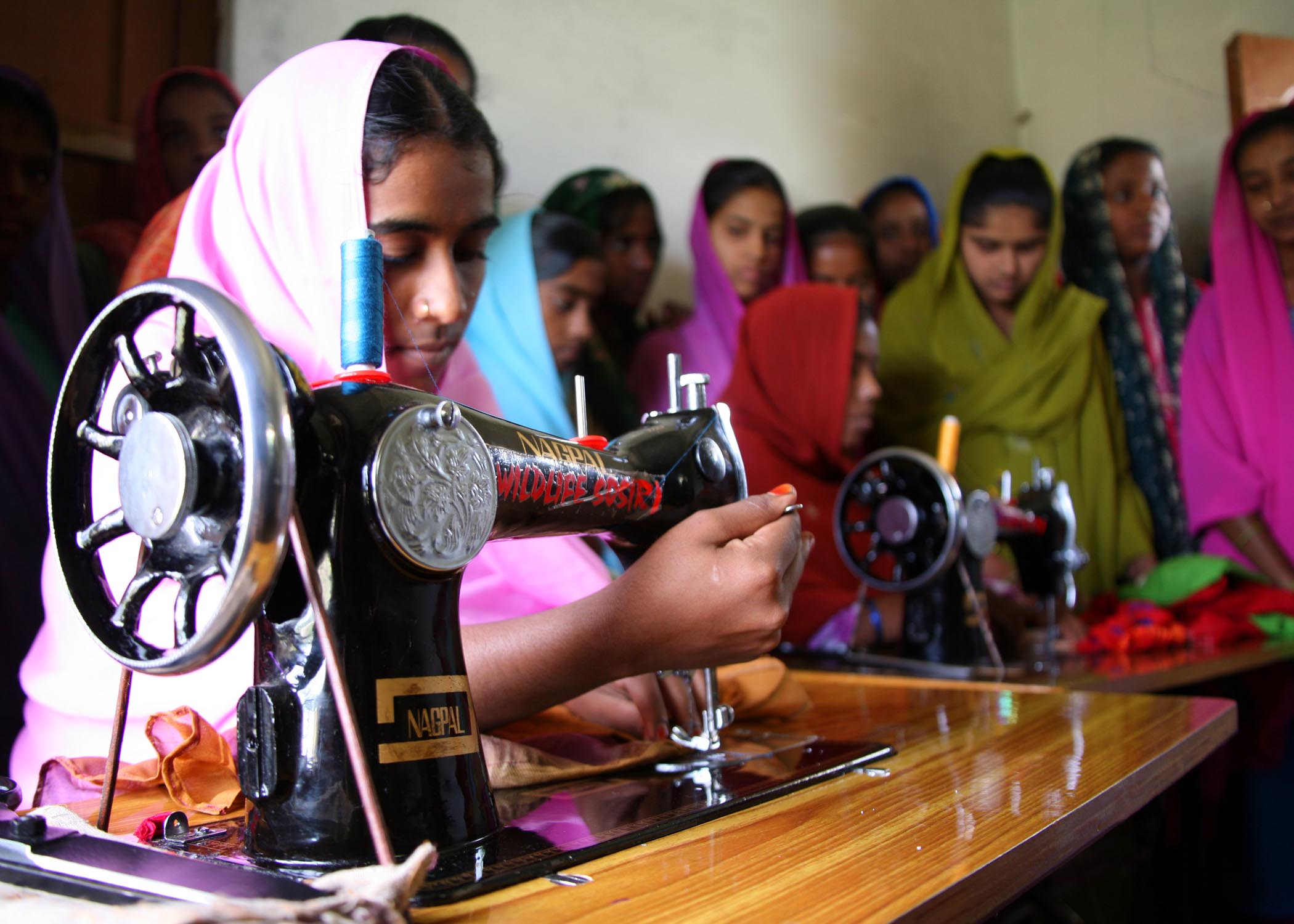 Kalandar woman in headscarf sewing.