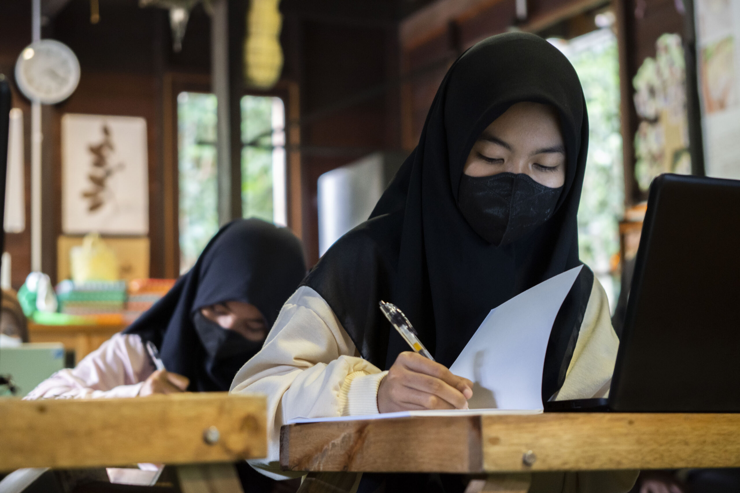 Young female students wearing headscarves in a classroom.